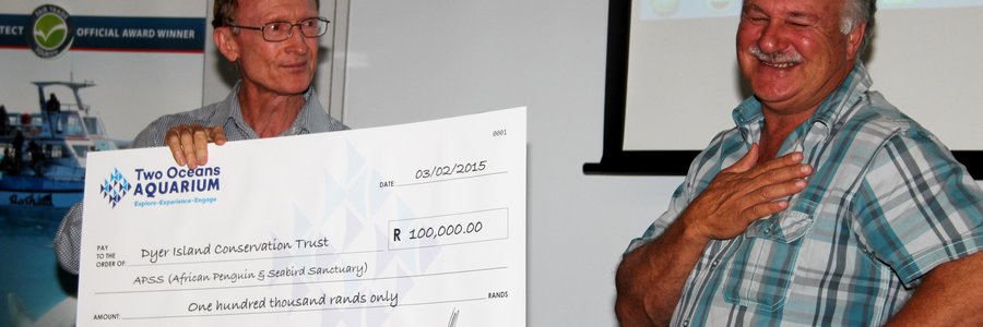 Dr Pat Garrat, uittredende Besturende Direkteur van die Twee Oseane Akwarium, oorhandig hier die tjek ten bedrae van R100,000 aan Wilfred Chivell